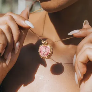 Detailed shot of a pink apple locket necklace with a delicate ballet dancer design