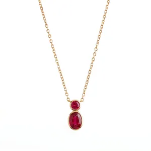 Macro view of gold bezel-set necklace featuring two vibrant red oval-cut stones