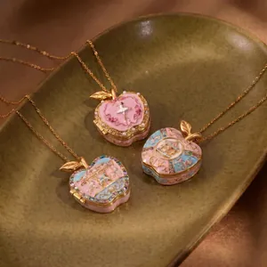 Detailed view of three carousel and ballerina apple locket pendants on a green plate