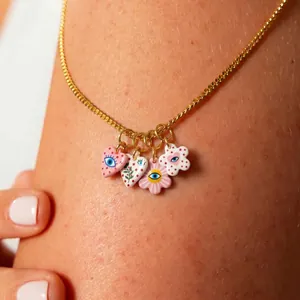 Macro detail of colorful heart and flower evil eye pendants on a gold chain
