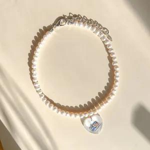 Elegante parelketting met een kleurrijke hartvormige hanger op een neutrale achtergrond