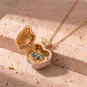 Close-up of pink and gold apple locket necklace showing a small horse charm inside