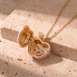 Detail view of open pink apple locket necklace with miniature rocking horse charm