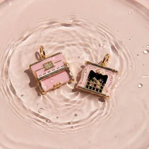 Gros plan de pendentifs en émail rose piano et cheminée dans des reflets d'eau.