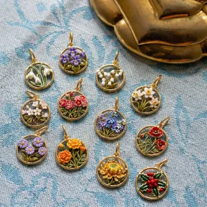 Detailed view of twelve different enamel birth flower pendants in gold finish.