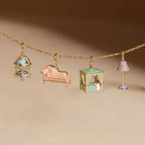 Vue détaillée de breloques en émail coloré en forme de meubles miniatures sur chaîne dorée
