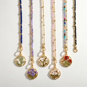 Close-up of stainless steel birth flower pendants with colorful beaded chains.
