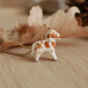 Ciondolo a forma di cane in ceramica fatto a mano con catena placcata oro 18K su foglie autunnali