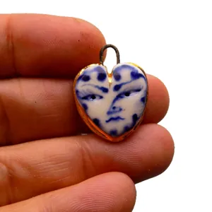 Pendentif en acier inoxydable en forme de cœur avec motif de visage bleu et blanc sur fond blanc