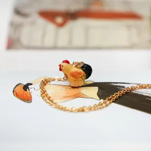 Detailed macro view of a cute colorful enamel rooster pendant on a fine gold-colored chain