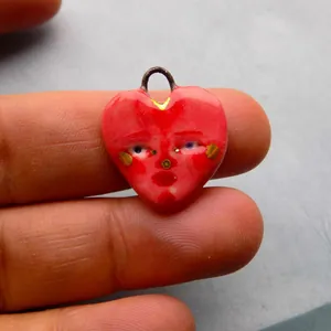 Gros plan d'un pendentif coeur rouge unique avec un détail de visage peint à la main