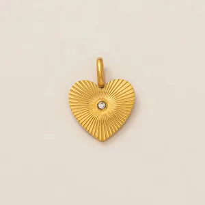 Detailed close-up of a gold heart pendant featuring a textured sunburst design and central stone.