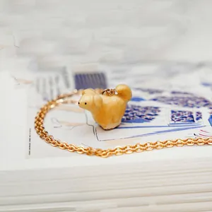 Macro view of a handcrafted cream-colored animal pendant on a delicate gold-tone chain.
