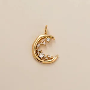 Close-up view of a gold crescent moon pendant with sparkling baguette and round stones