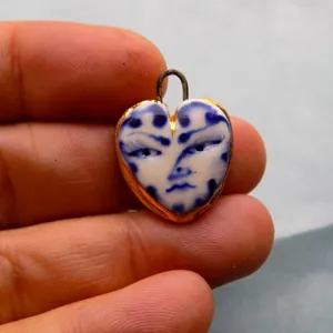 Gros plan du pendentif cœur avec motif de visage en porcelaine bleu et blanc