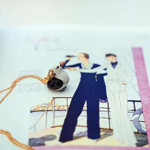 Close-up detail of a cute handmade ceramic bird pendant hanging on a dainty gold copper chain