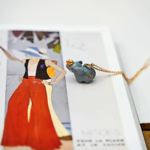 Close-up of a cute blue elephant pendant necklace with gold detail on a magazine page