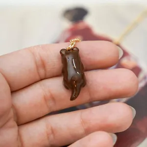 Close-up of a cute brown animal pendant held in hand, featuring a glossy finish.