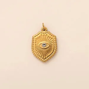 Macro detail of golden stainless steel shield pendant with sunburst evil eye design