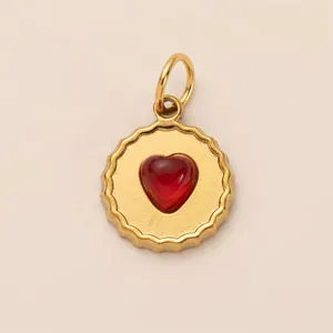 Close-up macro detail of gold scalloped round pendant with red heart shaped gemstone