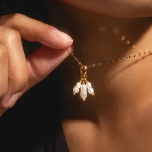Close-up of elegant gold necklace featuring three luminous baroque pearl charms