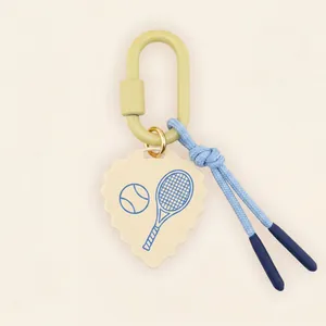 Detail of tennis racket print heart pendant keychain with green carabiner.