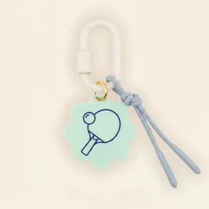 Close-up view of mint green flower-shaped tag featuring a blue ping-pong paddle print