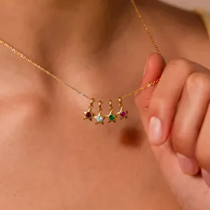 Primo piano di quattro ciondoli a stella dorati con pietre portafortuna colorate su collana