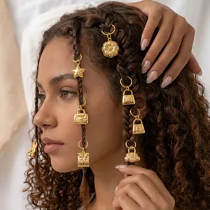 Detail view of golden charms braided into curly hair, featuring star and cloud designs