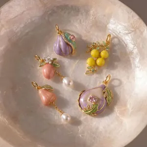 Gros plan détaillé de pendentifs en résine en forme de fruits avec perles et touches dorées.