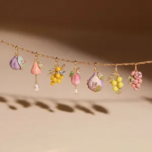 Gros plan détaillé de charms en émail en forme de fruits sur collier en titane doré