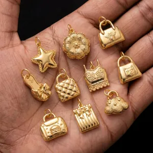 Detailed view of various 18K gold-plated stainless steel charms held in hand