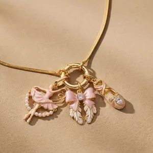 Close-up of pink ballerina, bow, and ballet shoe charms on a gold-plated necklace.