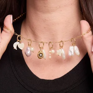 Vue détaillée d'un collier en chaîne dorée avec des breloques perles, lune, cœur et étoile sur un mannequin.