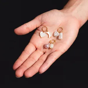 Détail des boucles d'oreilles en or avec pendentifs en perles et nacre en forme de cœur