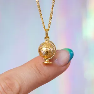 Detaillierte Nahaufnahme eines goldenen Reise-Globus-Anhängers mit glänzenden Kristallen