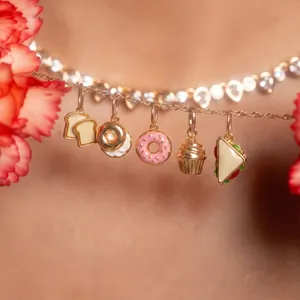 Detail of stainless steel gold necklace featuring cute bread and donut food charms.