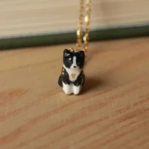 Gros plan d'un pendentif chat en céramique noir et blanc fait main avec un cœur doré
