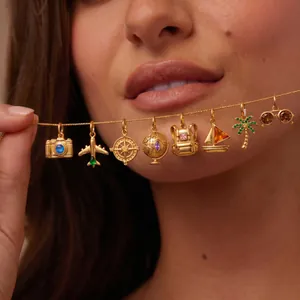 Macro detail of gold travel-themed charms including camera and globe on a necklace