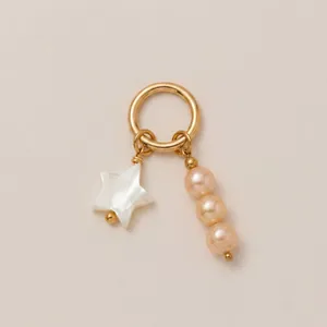 Détail exquis du pendentif étoile en nacre et de trois perles roses sur anneau doré