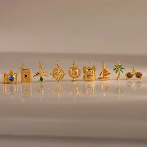 Collection of travel-themed gold charms including camera, airplane, and globe detail view
