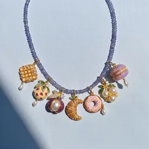Detailed view of food-themed pendants on a purple beaded necklace featuring donut designs.