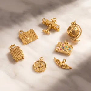 Detail view of 18K gold plated travel charms including airplane and globe on marble.