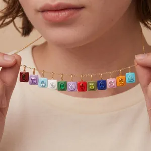 Primer plano de colgantes cuadrados de colores con piedras natales en cadena de oro