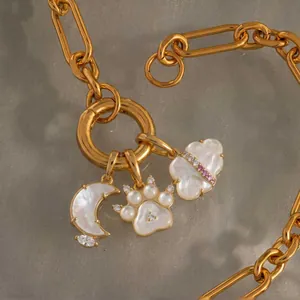Detail van gouden ketting met parelmoer maan, poot en wolk bedeltjes.