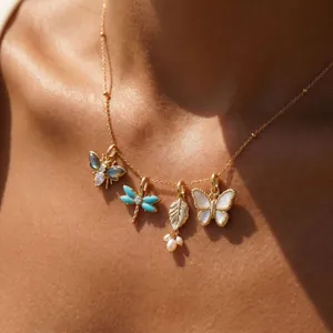 Detailed view of gold-plated necklace featuring butterfly, dragonfly, and leaf charms