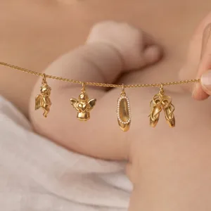 Detailed macro shot of gold-plated angel and ballet slipper charms on a fine chain