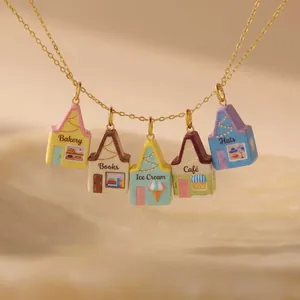 Detalle de cinco dijes de casas de colores en un collar con baño de oro de 18 quilates