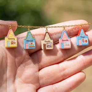 Primer plano de cinco dijes de casas en miniatura de colores en una cadena de acero dorado