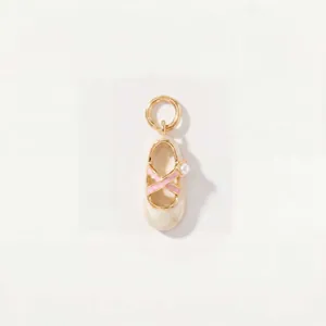 Vue détaillée d'un élégant pendentif chausson de danse crème avec ruban rose et perle.